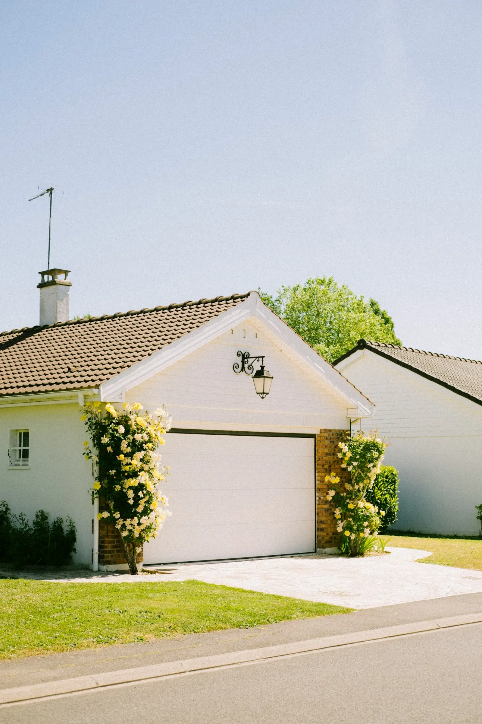 White cottage with a classic garage door and climbing roses