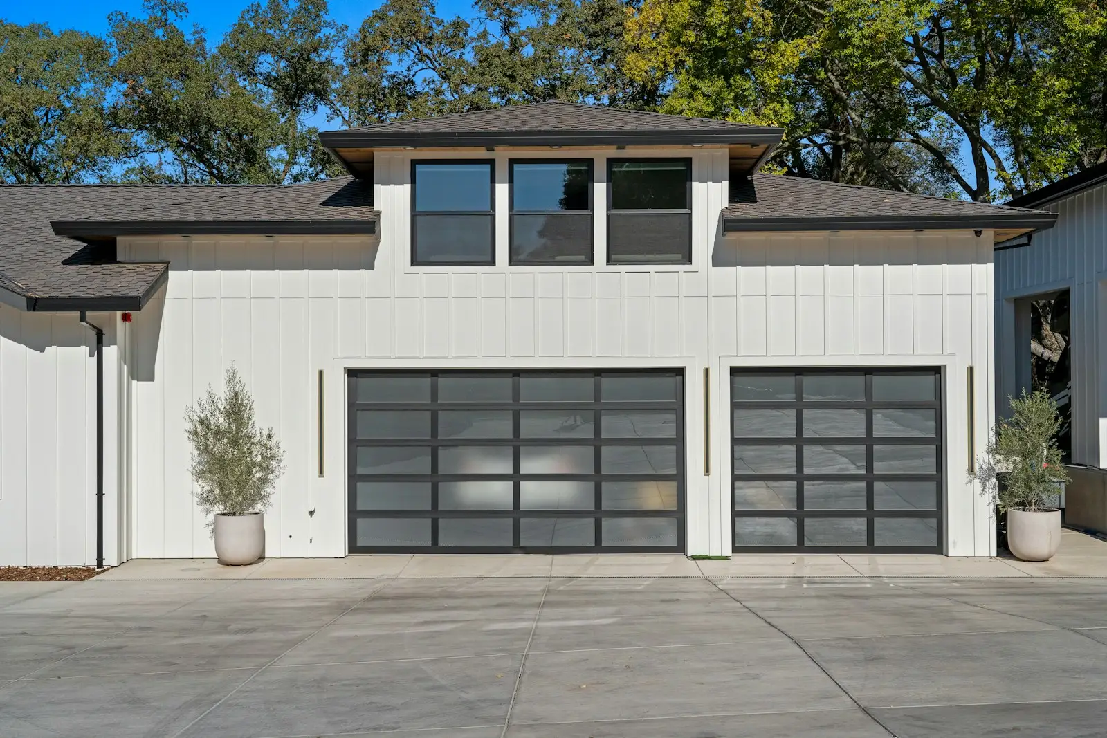 Modern white farmhouse with black full-view glass garage doors