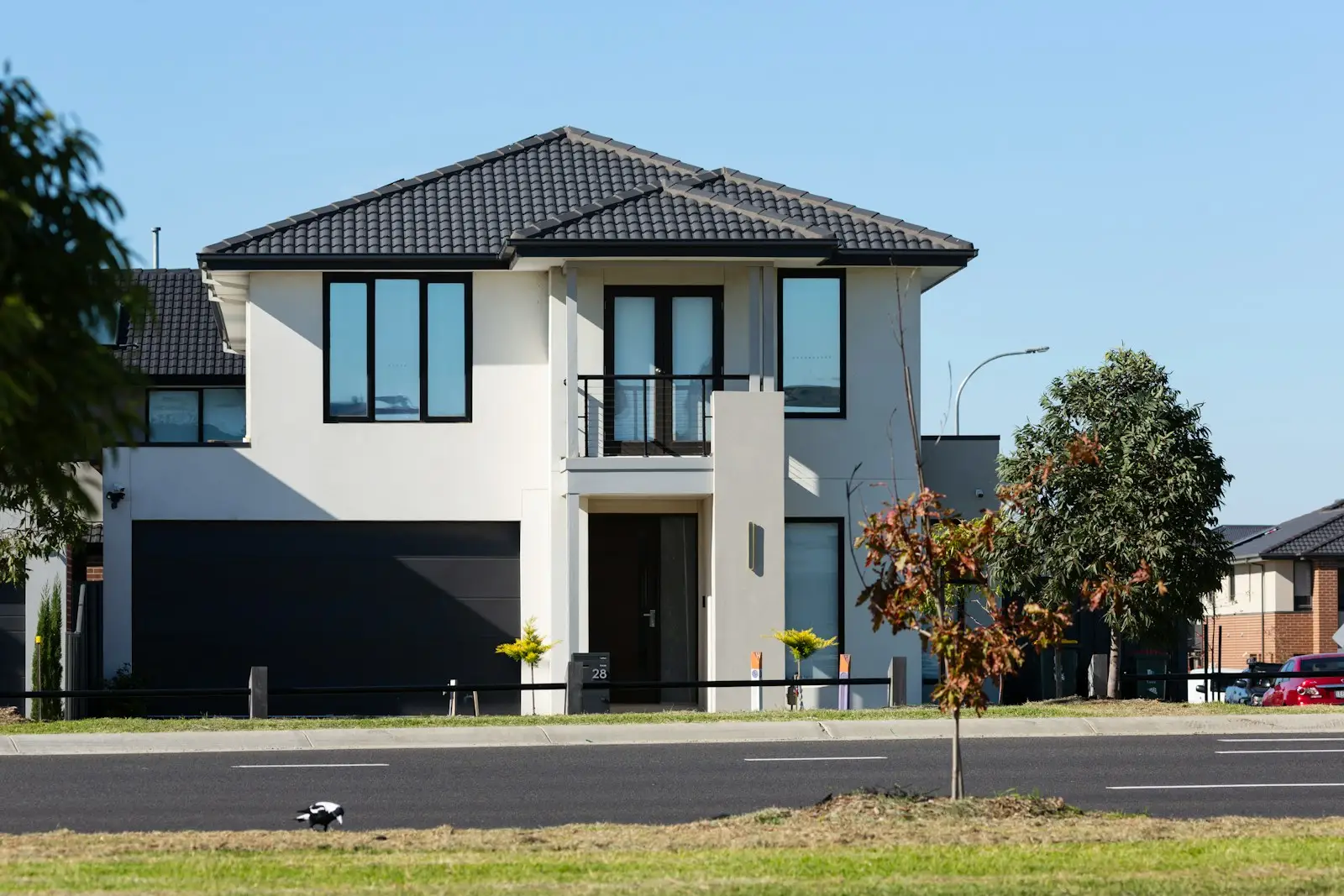 Modern white farmhouse with black full-view glass garage doors